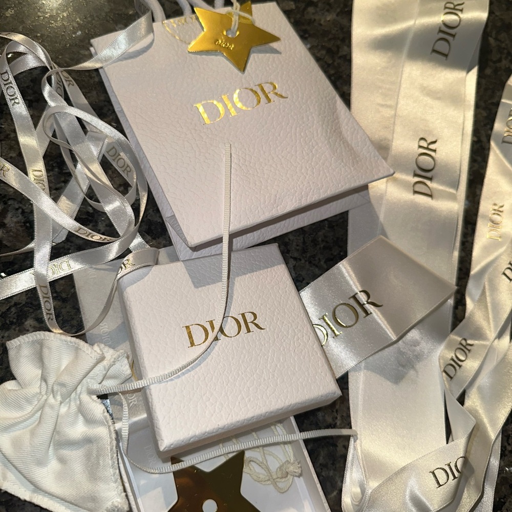 Two Dior Gold Star purse charms and packaging